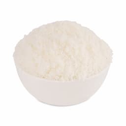 Finely grated dry coconut in a bowl with whole coconut pieces arranged beside it